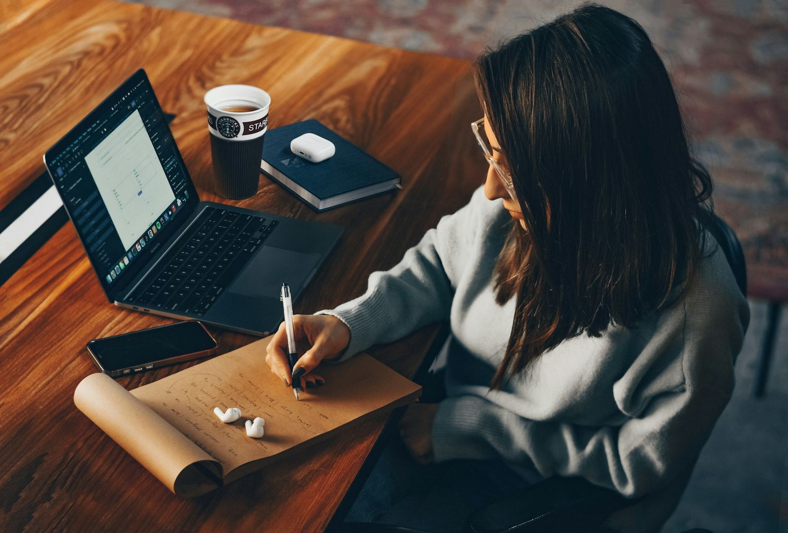 A woman planning a newsletter in a notebook beside her laptop